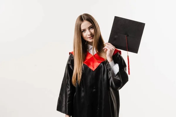 Cheerful bachelor girl in graduation robe and cap on white background. Happy and funny young woman smile. Student achieve master degree in univesity