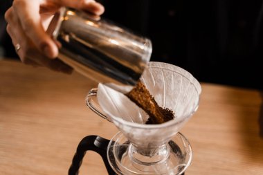 Barista çaydanlıktan su dökmeden önce kağıt filtresinin üzerine öğütülmüş kahve döktü. Kafede filtre kahvenin üzerine demleme işlemi