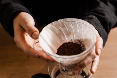 Barista su dökmeden önce kağıt filtreye öğütülmüş kahve döker. Kafede filtre kahvenin üzerine demleme işlemi