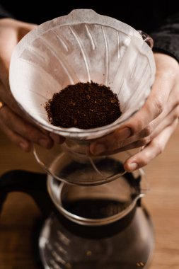 Barista su dökmeden önce kağıt filtreye öğütülmüş kahve döker. Kafede filtre kahvenin üzerine demleme işlemi
