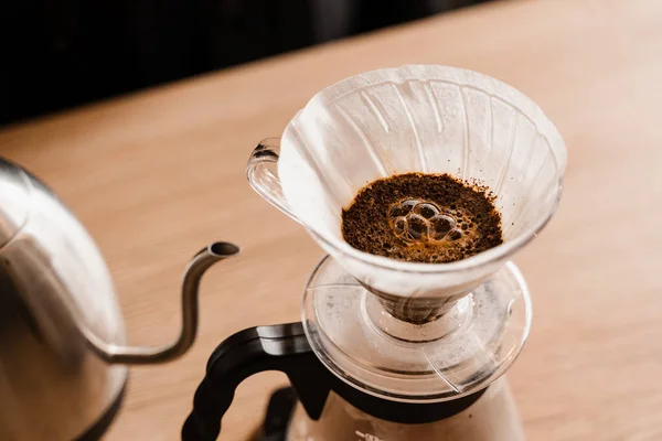 Stock image Pour over filter with ground coffee in the funnel in focus. Drip filter coffee brewing. Pour over alternative method of pouring water over roasted and ground coffee beans contained in filter