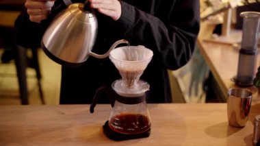 4k video Barista hunide öğütülmüş kahveyle sıcak suyu filtreden döküyor. Damlatma filtresi kahvesi demleniyor. Alternatif su dökme metodunu filtrede bulunan kahve çekirdeklerinin üzerine dökün..