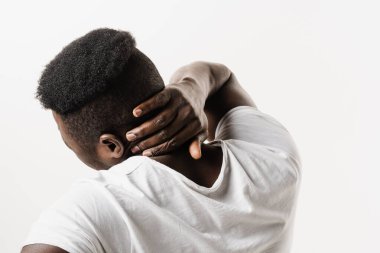 Afrikalı adam, beyaz arka planda omurga ve boyun ağrısı hissediyor. Servikal omurga osteokondrosis Afro-Amerikan erkeklerinin radikal sendromlarıdır.