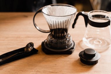 Kafedeki ahşap masaya filtre ve aksesuarların üzerine dökülen akıllı kahve damlası. Damlatma filtresi kahvesi demleniyor. Zeki kahve damlası evde filtre kahve yapmak için alternatif bir yöntem.