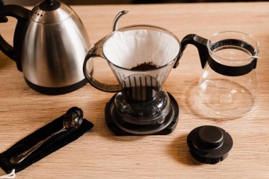 Kafedeki ahşap masaya filtre ve aksesuarların üzerine dökülen akıllı kahve damlası. Damlatma filtresi kahvesi demleniyor. Zeki kahve damlası evde filtre kahve yapmak için alternatif bir yöntem.