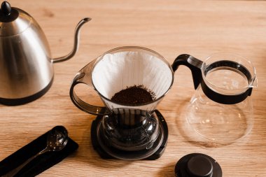 Kafedeki ahşap masaya filtre ve aksesuarların üzerine dökülen akıllı kahve damlası. Damlatma filtresi kahvesi demleniyor. Zeki kahve damlası evde filtre kahve yapmak için alternatif bir yöntem.