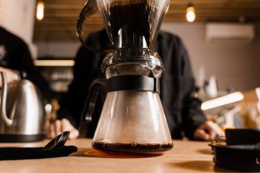 Kafedeki filtreden dökülen akıllı damlatıcıdan demliğe kahve dolduruyorum. Evdeki akıllı damlatıcıyla kahve demlemek için alternatif bir yöntem. Barista kafede akıllı kahve damlatıcısı yapıyor.