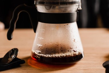 Kafedeki filtreden dökülen akıllı damlatıcıdan demliğe kahve dolduruyorum. Evdeki akıllı damlatıcıyla kahve demlemek için alternatif bir yöntem. Barista kafede akıllı kahve damlatıcısı yapıyor.
