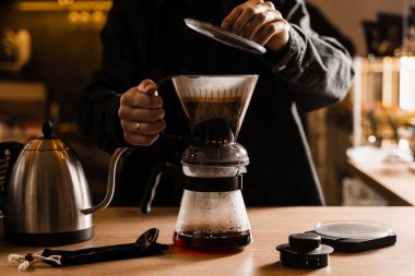 Kafedeki ahşap masaya filtre ve aksesuarların üzerine dökülen akıllı kahve damlası. Damlatma filtresi kahvesi demleniyor. Zeki kahve damlası evde filtre kahve yapmak için alternatif bir yöntem.