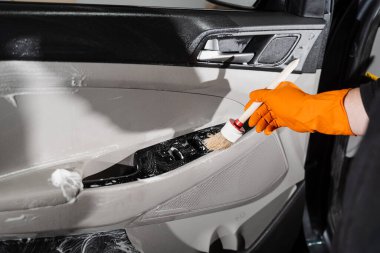 Araba düğmelerini köpükle fırçalama işlemi ve araba kapısı paneli deterjanı. Araba temizleme servisi. Müşterilerin iç çamaşırlarını yıkayan temizlik işçisi