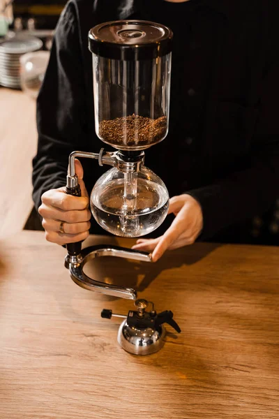 カフェでサイフォンコーヒーを醸造するプロセス バリスタはサイフォンを持ってるサイフォンの中で沸騰した水を始める前に — ストック写真