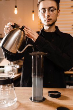 Barista bir çaydanlıktan diğerine sıcak su döküyor. Bira üreten uçaklar. Kavrulmuş sıcak su dökülüyor ve kahve çekirdekleri uçakla eziliyor.