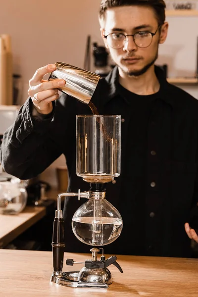 stock image Barista pour ground coffee over syphon before starting boiling water inside siphon. Process of brewing syphon coffee in cafe