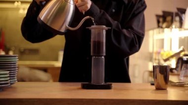 4K video barista kafede uçak kahvesi yapıyor. Kahve yapmak için alternatif uçak metodu. Kavrulmuş sıcak su dökülüyor ve kahve çekirdekleri uçakla eziliyor..