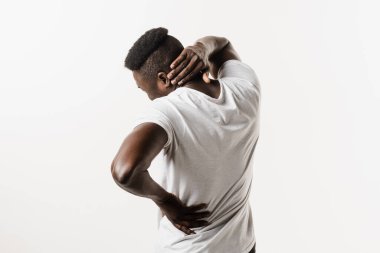 Afrikalı adam, beyaz arka planda omurga ve boyun ağrısı hissediyor. Servikal omurga osteokondrosis Afro-Amerikan erkeklerinin radikal sendromlarıdır.