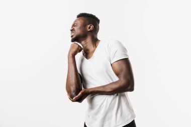 Dirsek yaralanması ağrıya, şişliğe, sertliğe ve sınırlı hareketlere neden olur. Kırıklar, çıkıklar, burkulmalar ve tenis dirseği. Beyaz arka planda izole edilmiş Afrikalı Amerikalı bir adamın dirsek yaralanması.