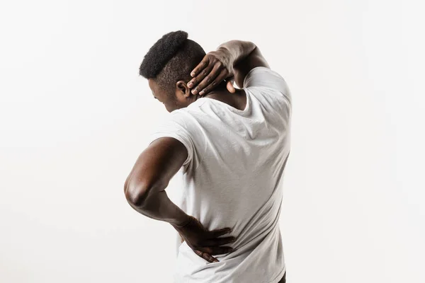 African man feel spine and neck pain because of spinal nerves compression on white background. Cervical spine osteochondrosis is radicular syndromes of african american man