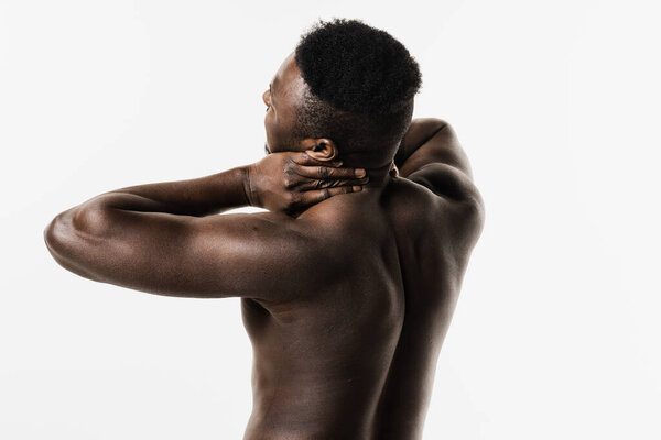 Cervical spine osteochondrosis is radicular syndromes of african american man. Muscular shirtless african man feel spine and neck pain because of spinal nerves compression on white background
