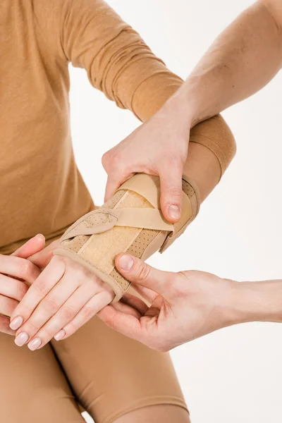 外傷科医は 損傷から回復し 新しい傷害のリスクを軽減するために手に女の子に外部手首包帯を置きます 手首関節の病理学的可動性を減少させるために外的矯正を手首 — ストック写真