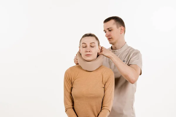 Neurosurgeon puts cervical soft collar or neck brace bandage on young woman to support and immobilize neck or for treat traumatic head or neck injuries. Cervical collar