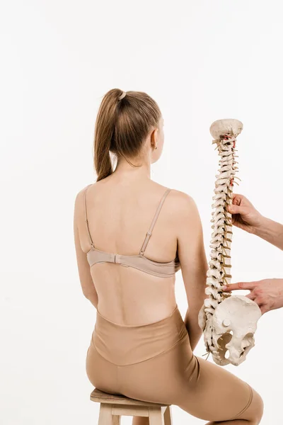 Scoliosis is sideways curvature of the spine. Backbone anatomical model with young woman. Orthopedist showing spinal column model with girl on white background