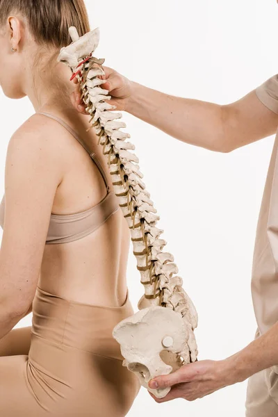 脊柱侧弯是脊柱侧弯 后骨解剖模型与年轻女子 有白人背景的女孩的脊柱模型的矫形外科医生 — 图库照片
