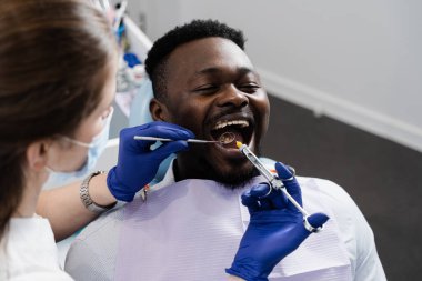 Dişçi Afrikalı hastaya hastalıklı dişlerin anestezi şırıngasını enjekte ediyor. Karne tedavisi