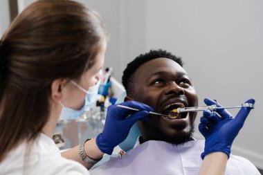 Anestezi şırıngası yakın çekim. Dişçi, hastalıklı dişlerin tedavisi için Afrikalı adamın ağzına anestezi enjekte ediyor. Karne tedavisi