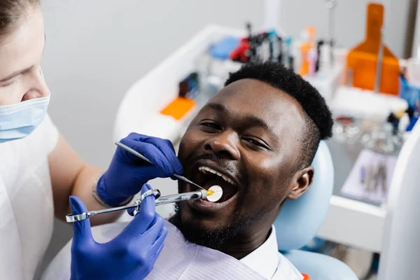Dentist injects syringe with anesthesia in mouth of african man for treatment of diseased teeth. Caries treatment. Anesthesia syringe injection