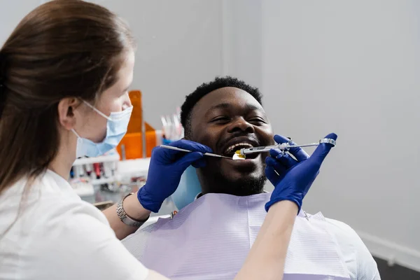 Dentist injects syringe with anesthesia in mouth of african man for treatment of diseased teeth. Caries treatment. Anesthesia syringe injection