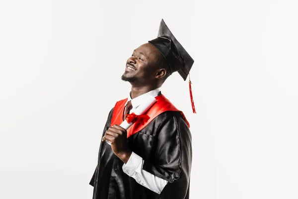 Graduate african man with master degree in black graduation gown and cap on white background. Happy african student successfully graduated from the university with honors
