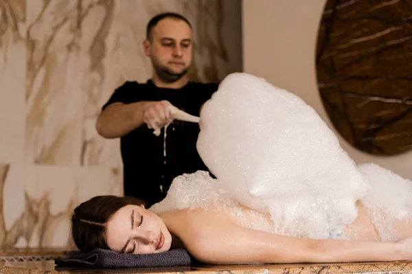 スパでリラックスした魅力的な女の子 Masseurはトルコのスパハマムで泡剥離を作っています — ストック写真