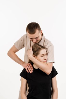 Ortopedist kadın boynunu ve kafasını muayene ediyor. Sırtın ve boyun bölgesinin elle düzeltilmesi. Beyaz arka planda rehabilitasyon terapisi. Fizyoterapist ya da masörde elle tedavi.