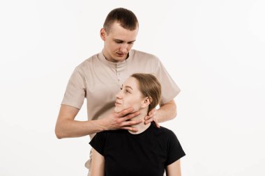 Fizyoterapist ya da masörde elle tedavi. Ortopedist kadın boynunu ve kafasını muayene ediyor. Sırtın ve boyun bölgesinin elle düzeltilmesi. Beyaz arka planda rehabilitasyon terapisi