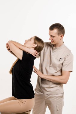 Fizyoterapist ya da masörde elle tedavi. Ortopedist kadın boynunu ve kafasını muayene ediyor. Sırtın ve boyun bölgesinin elle düzeltilmesi. Beyaz arka planda rehabilitasyon terapisi