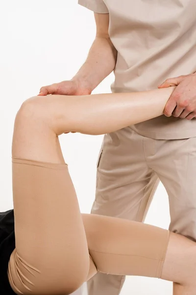 Knee joint and meniscus injury on white background. Orthopedist is touching and pressing knee for assessment of the volume of physiological movements. Examination of knee mobilisations