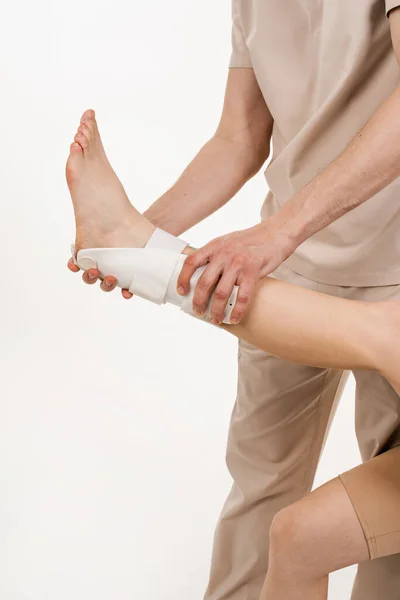 Traumatologist puts external ankle or foot bandage on leg to recover from injuries and reduce risk of new injuries. Ankle and foot external orthosis to reduce pathological mobility of ankle joints