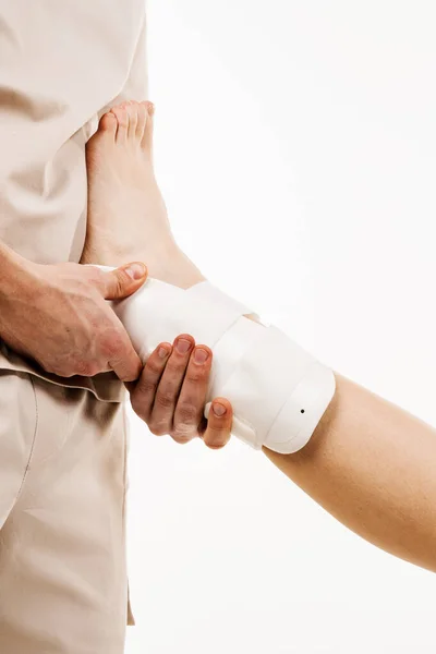 Ankle and foot external orthosis to reduce pathological mobility of ankle joints. Traumatologist puts external ankle or foot bandage on leg to recover from injuries and reduce risk of new injuries
