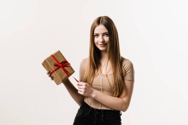 Beyaz arka planda hediye kutusu olan neşeli bir kız. Gülümseyen, hediyesini tutan ve doğum gününde ya da diğer tatillerde hediye alan mutlu genç bir kadın. Olay kutlaması