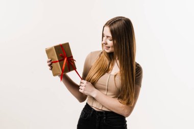 Beyaz arka planda hediye kutusu olan neşeli bir kız. Gülümseyen, hediyesini tutan ve doğum gününde ya da diğer tatillerde hediye alan mutlu genç bir kadın. Olay kutlaması