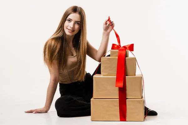 Cheerful girl with gift box with present on white background. Happy young woman smiling and holding gift and present received on birthday or other holiday. Event celebration