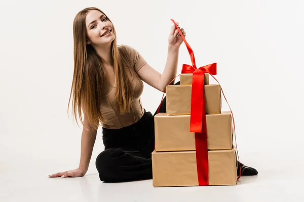 Cheerful girl with gift box with present on white background. Happy young woman smiling and holding gift and present received on birthday or other holiday. Event celebration