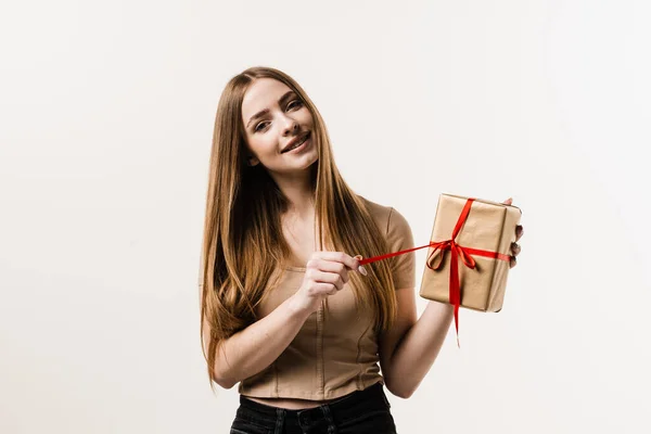 stock image Happy young woman smiling and holding gift and present received on birthday or other holiday. Event celebration. Cheerful girl with gift box with present on white background