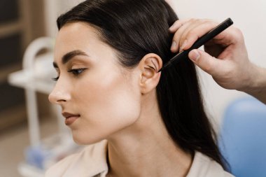 Pinna ve kulak cerrahi yeniden şekillendirme için Otoplasty işareti. Kulak ameliyatından önce göz kapağı ameliyatı. Cerrah otoplasti estetik ameliyatından önce kulağına işaret koymuş.