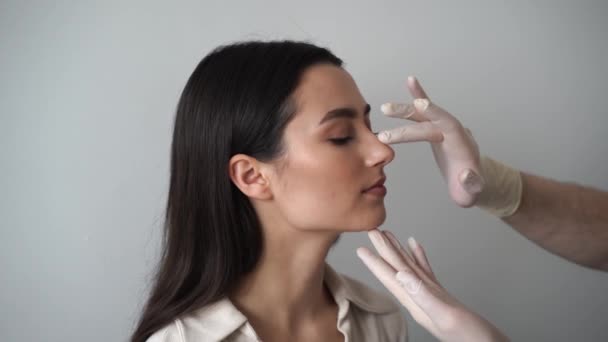 4Kビデオ鼻形成術は 鼻の外観を変更し 呼吸を改善するための鼻手術を改革しています 耳鼻咽喉科は整形前に鼻とコンサルティングの女の子患者に触れています — ストック動画