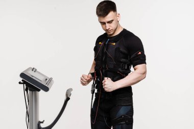 Beyaz arka planda EMS kıyafetli kaslı erkek sporcu. Elektrik kas stimülasyonu giysisinde spor eğitimi