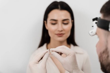 Burun debriyajı, burun içinde tutulan iki parça plastiktir. KBB doktoru septoplasti ameliyatından önce hastaya burun debriyajı gösteriyor.