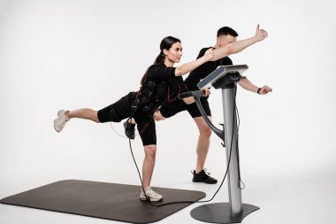 EMS giysisi içinde grup çalışması, kasları çalıştırmak için elektriksel impulslar uyguluyor. Antrenör, EMS elektriksel kas stimülasyonu giysisi kullanarak egzersiz örneği gösteriyor.