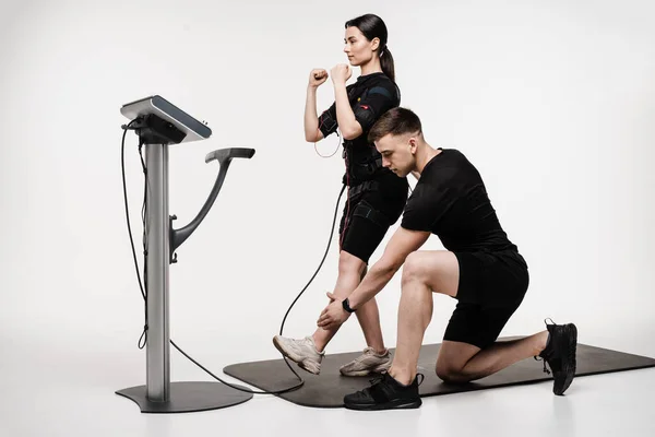 stock image Group workout training in EMS suit, which applies electrical impulses to activate muscles. Trainer shows an example of the exercise using EMS electrical muscle stimulation suit