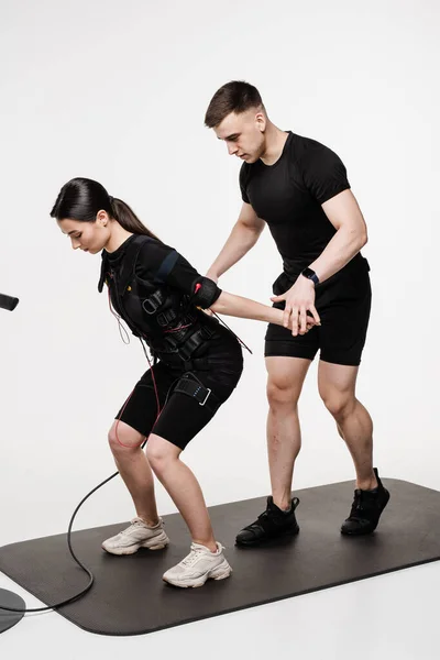 stock image Group workout training in EMS suit, which applies electrical impulses to activate muscles. Trainer shows an example of the exercise using EMS electrical muscle stimulation suit